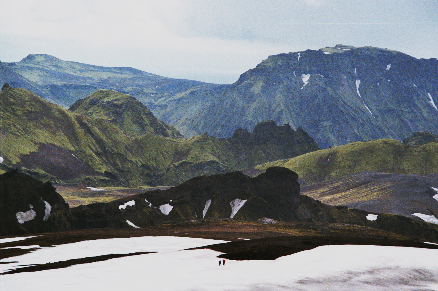 Two people walking in the snowy mountains of Iceland.